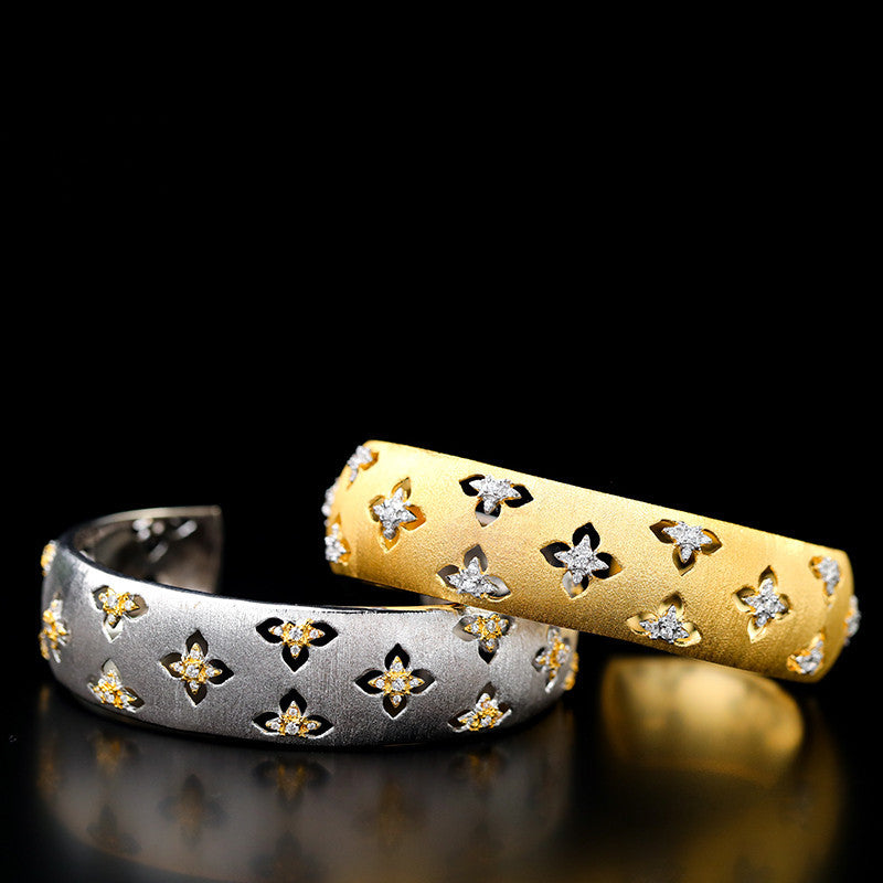 Two gold and silver rings with floral designs on a black background