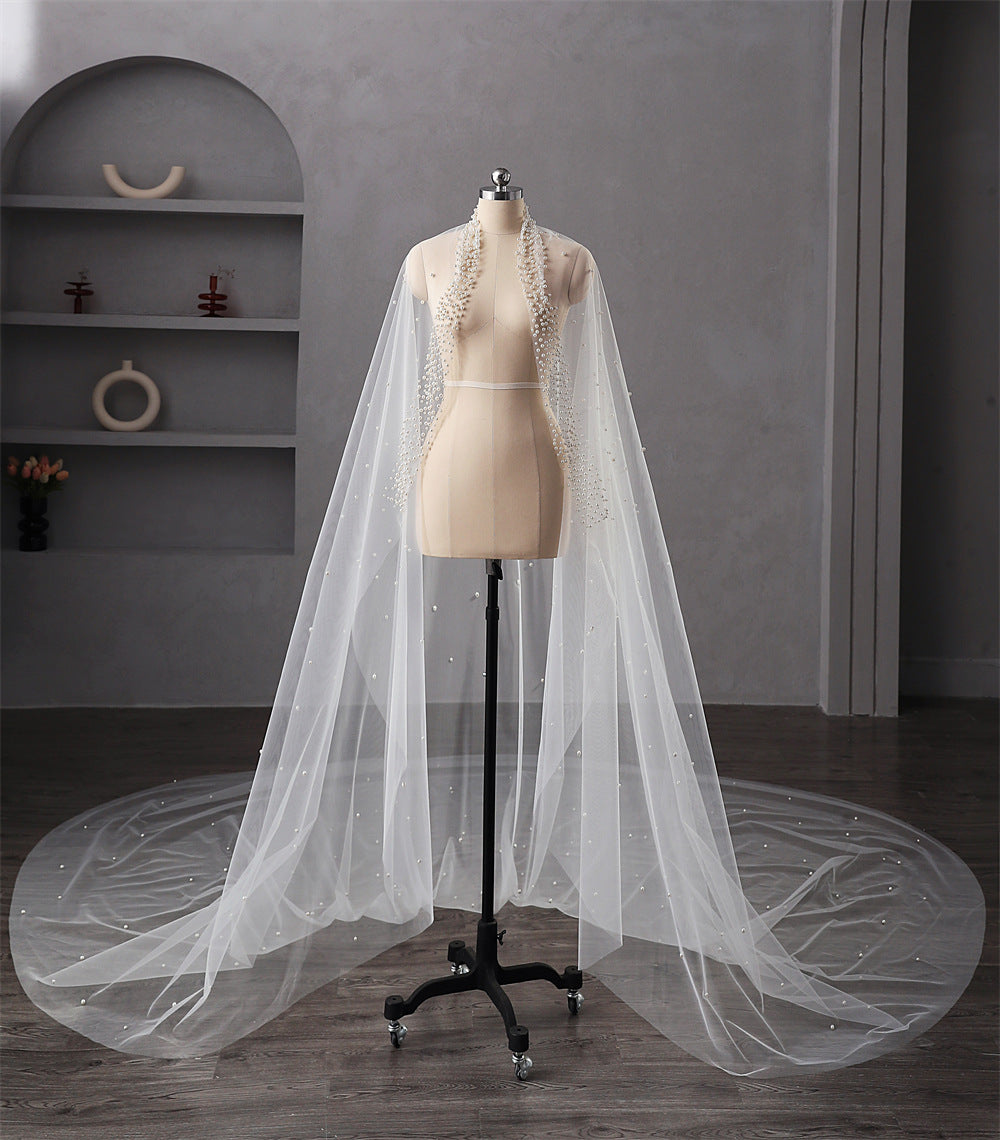 White bridal veil on a mannequin stand against a gray wall.