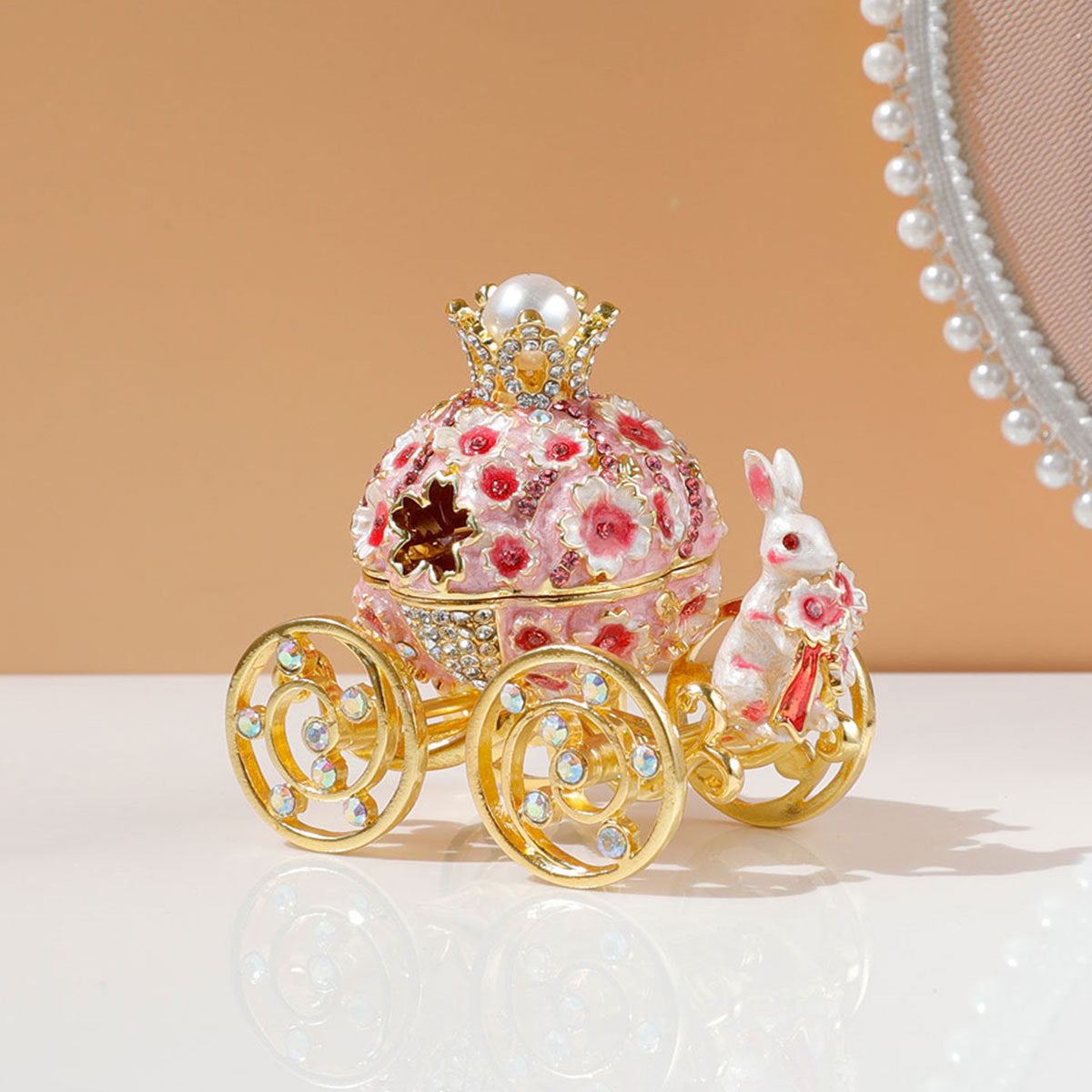 Decorative Easter egg with floral design and rabbit figure on a reflective surface.