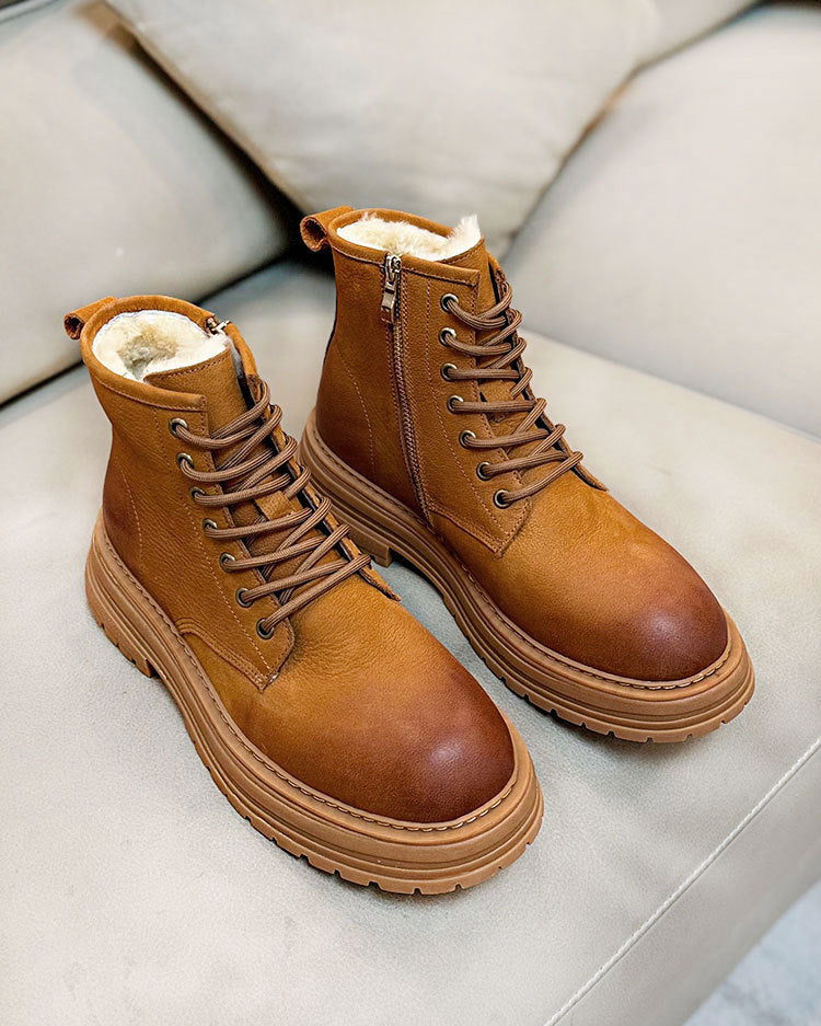 Pair of brown leather boots with fur lining on a light gray surface