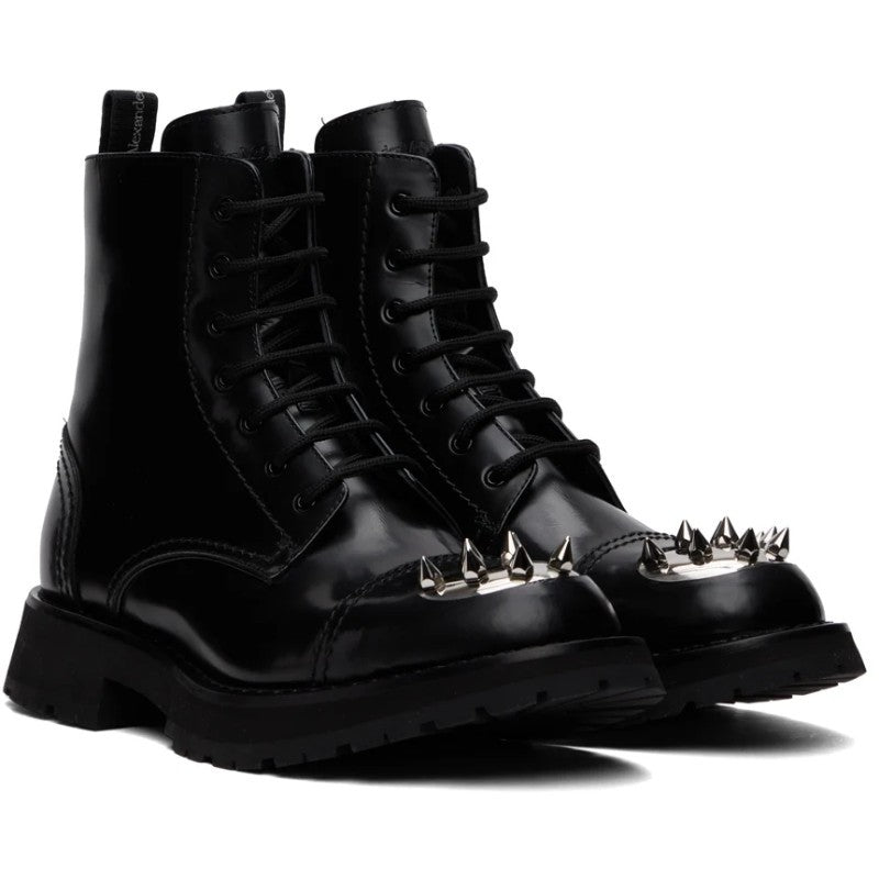 Black leather boots with spike details on a white background