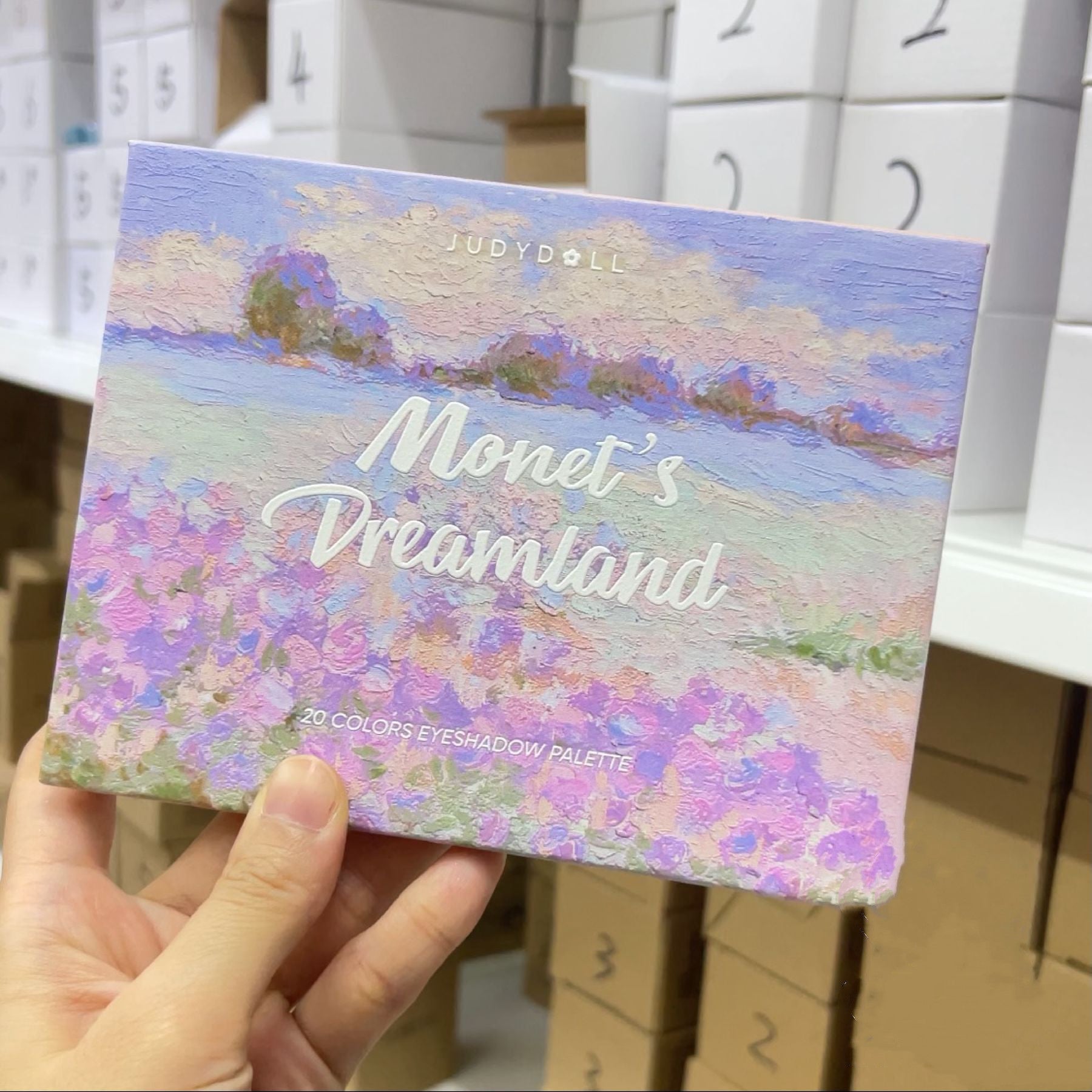 Judydoll Monet's Dreamland eyeshadow palette held by a hand with blurred background