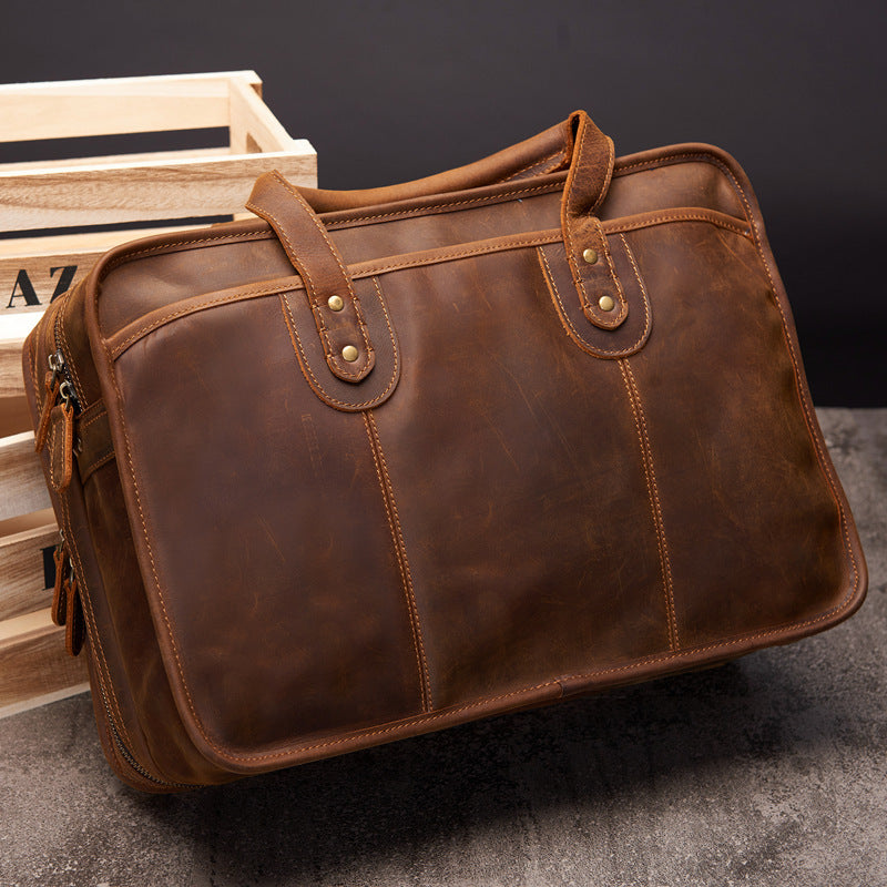 Brown leather briefcase on a dark surface with a wooden crate in the background
