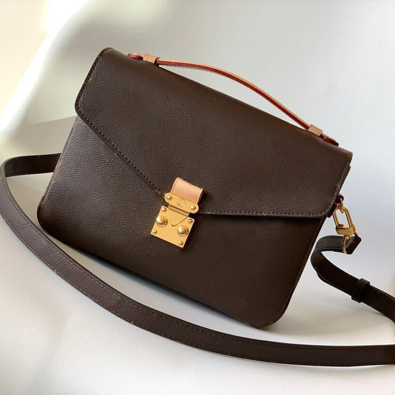 Brown leather handbag with gold clasp on a light background