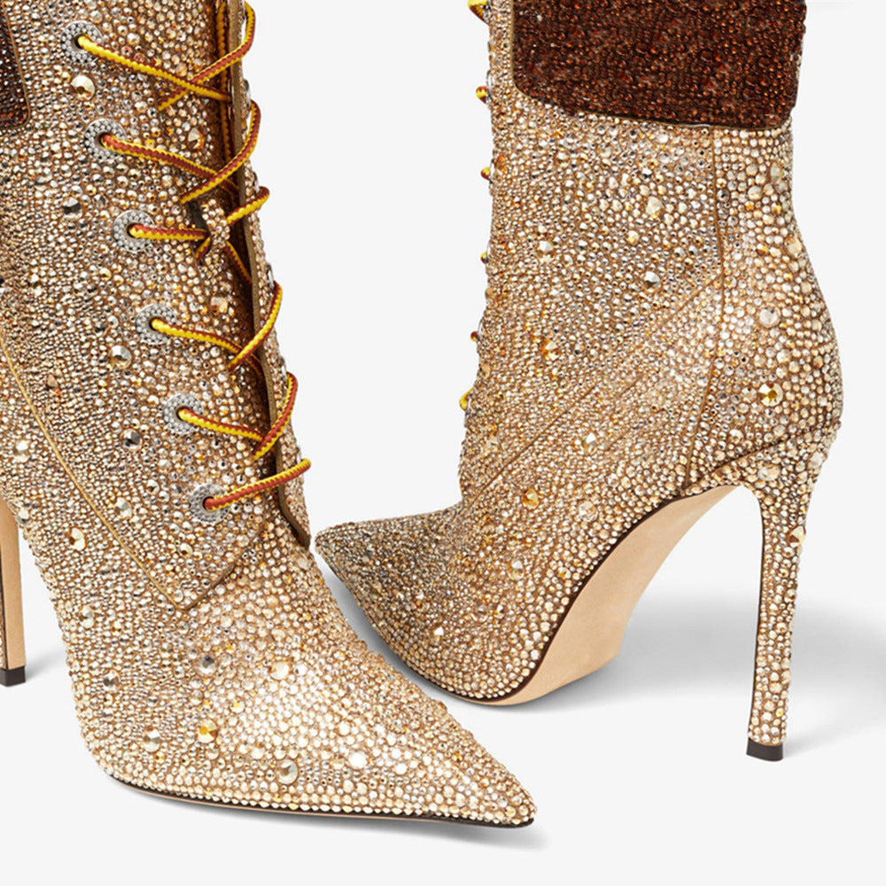 Gold studded high-heeled boots with decorative laces on a white background