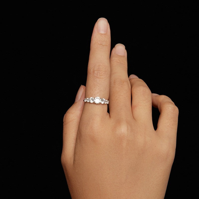 Hand wearing a silver ring on a black background