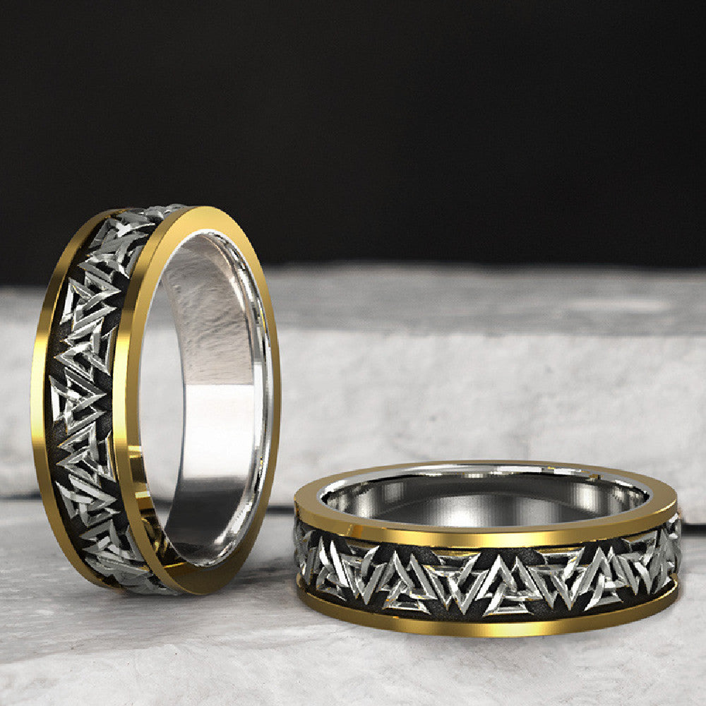 Two gold and silver rings with geometric patterns on a dark background