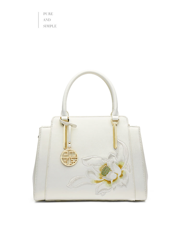 White handbag with floral design and gold accents on a white background