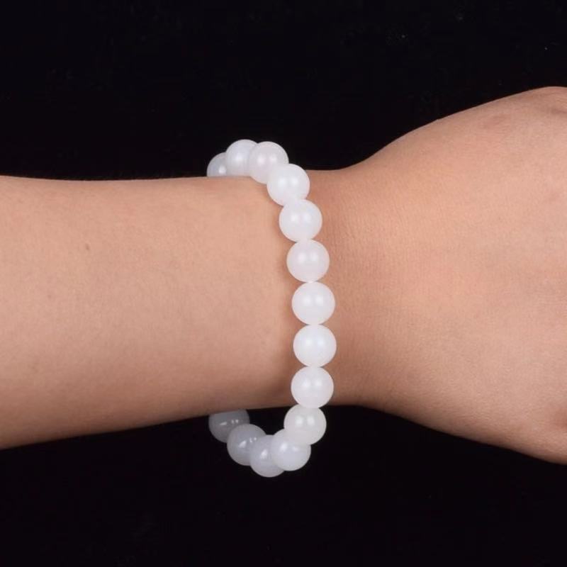 White beaded bracelet on a wrist against a black background