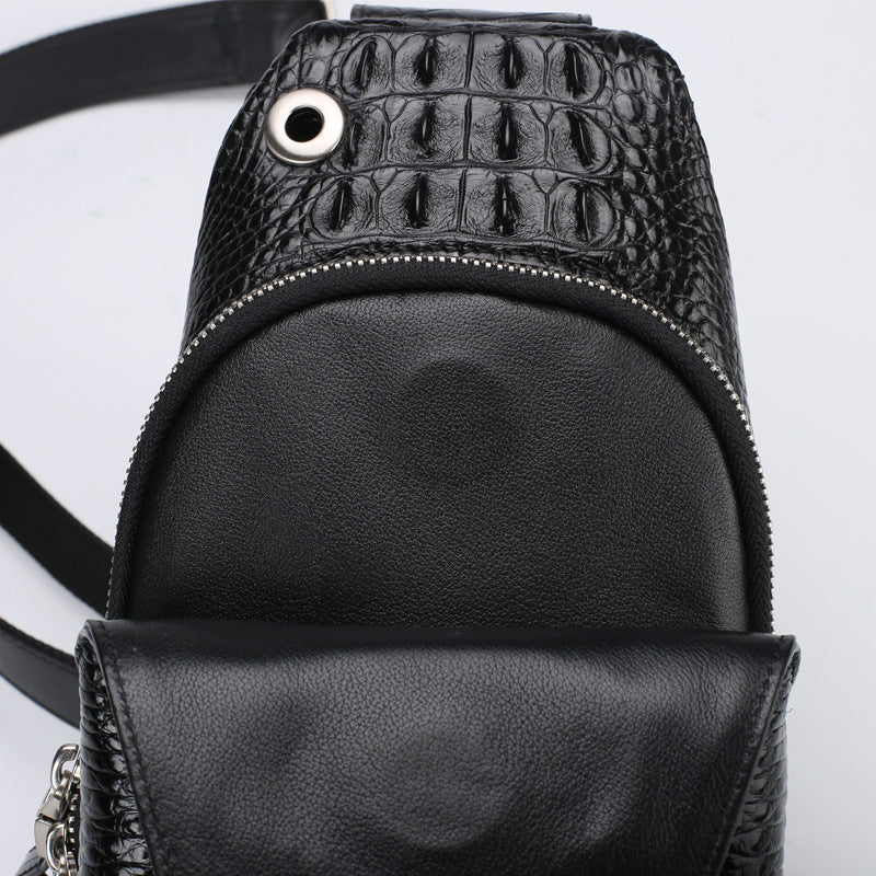Black leather backpack with crocodile texture on a light gray background