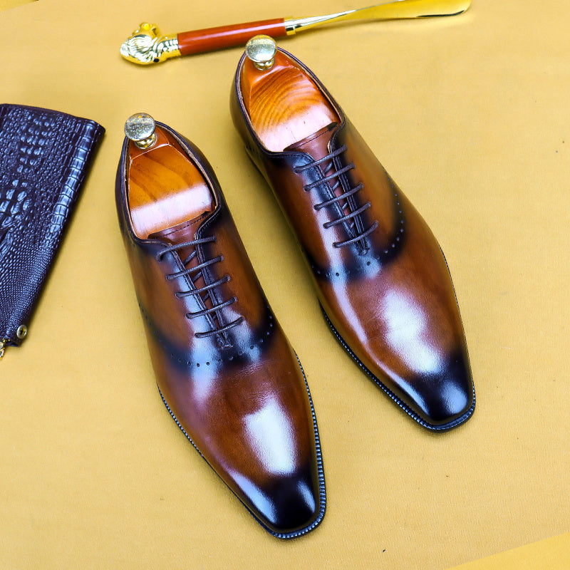 Pair of brown leather dress shoes with a gold tool on a beige background