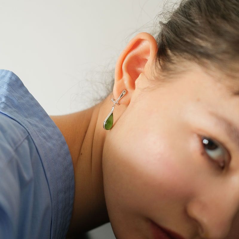 Close-up of a person wearing a green earring with a blurred background