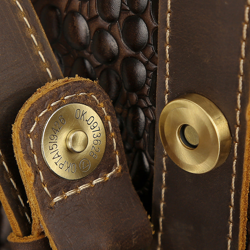 Close-up of a brown leather product with gold metal components and visible stitching.