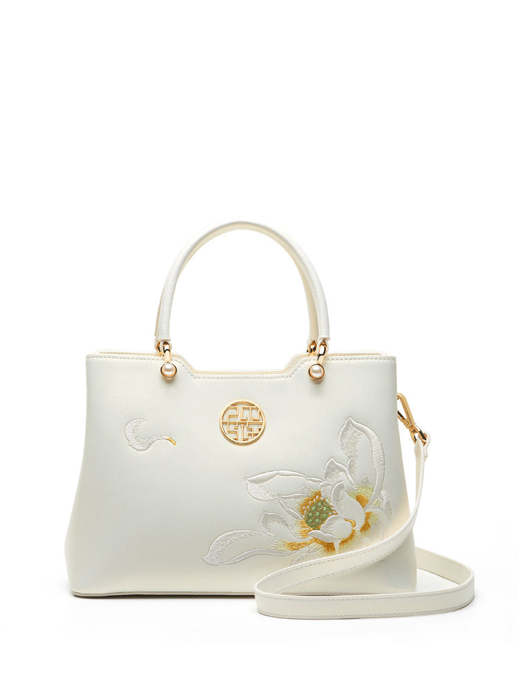 White handbag with floral embroidery and gold accents on a white background