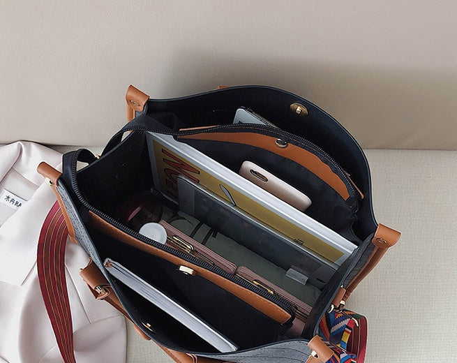 Open leather bag with compartments and items on a light surface