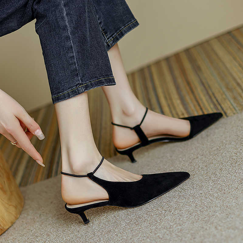 Black kitten heel shoes worn with blue jeans on a neutral background
