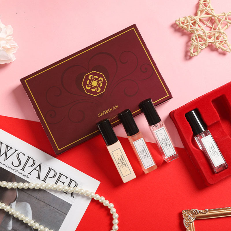 Set of perfume bottles and a box on a red surface with a pink background