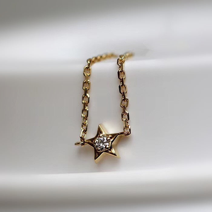 Gold star-shaped necklace with diamond-like stones on a white background