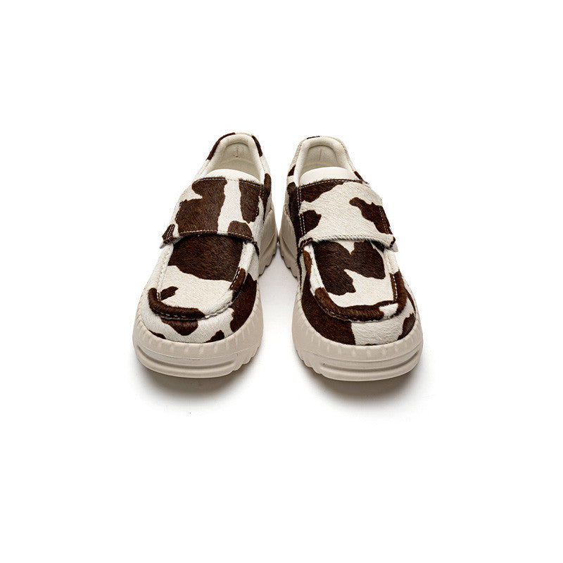 Pair of cow print shoes on a white background