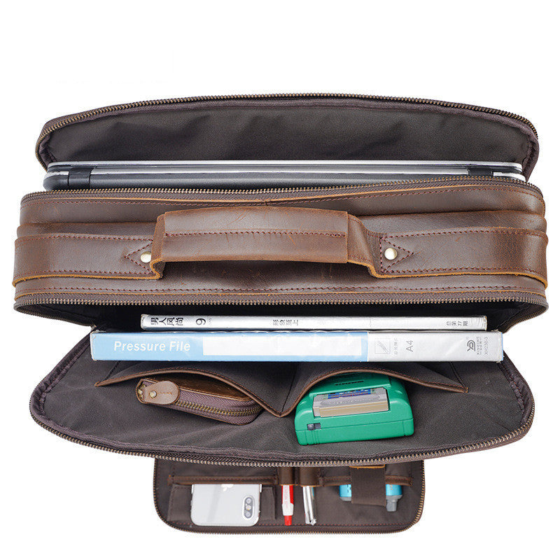 Brown leather briefcase with compartments and items inside on a white background