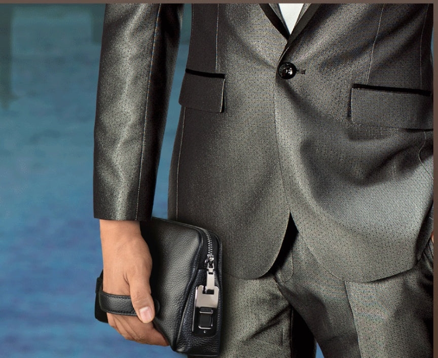 Person wearing a gray suit holding a black leather briefcase against a blue background