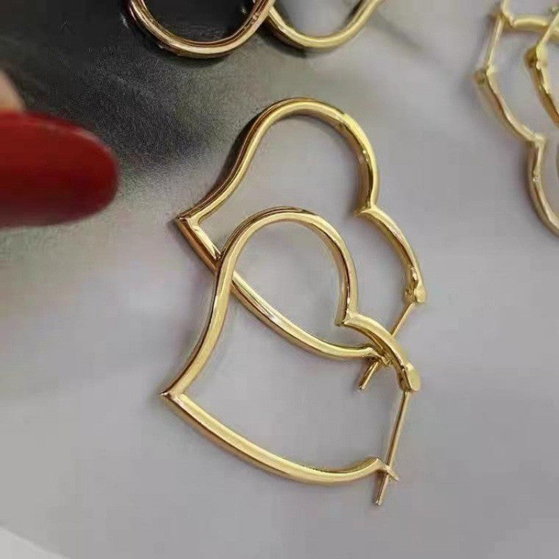 Gold heart-shaped hoop earrings on a light gray background