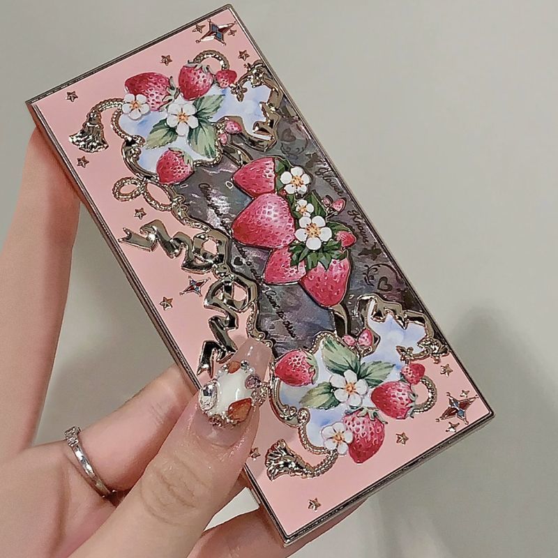 Decorative phone case with strawberry and floral design held by a hand.