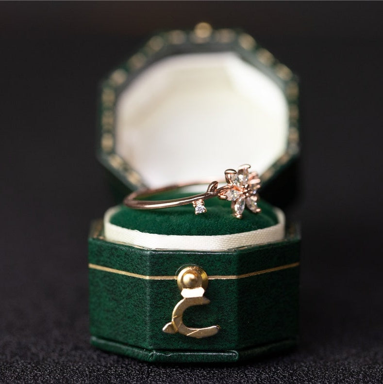 Gold ring with diamonds in a green velvet box on a dark background