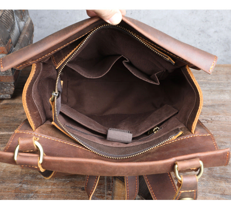Brown leather bag with gold zippers on a wooden surface