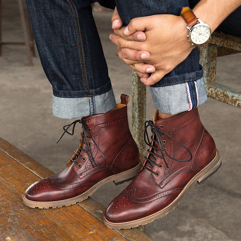 Brown leather boots worn with rolled-up jeans on a wooden floor.