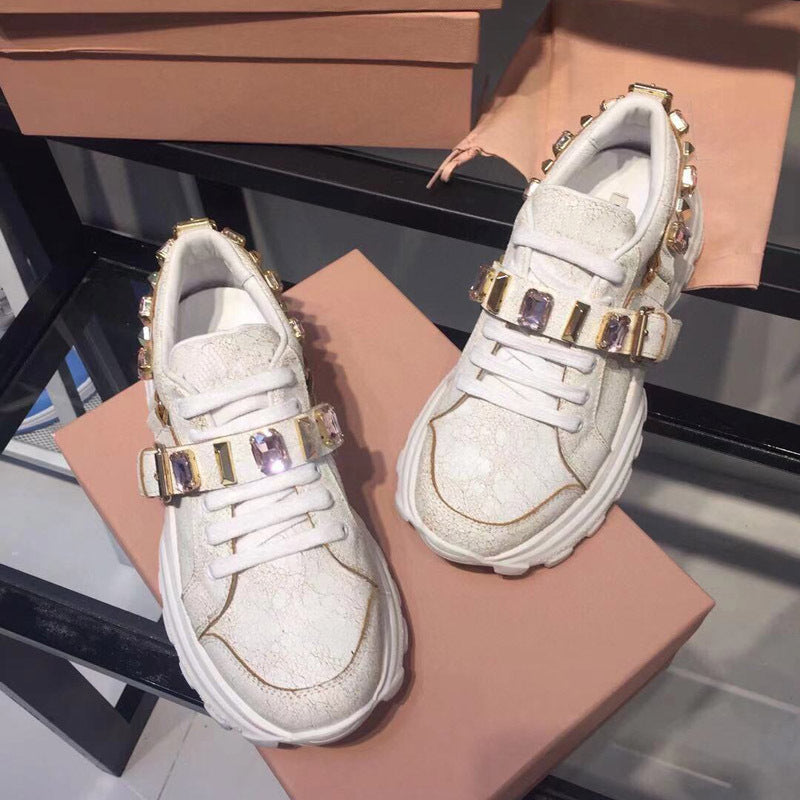 White sneakers with gold and purple accents on a pink surface
