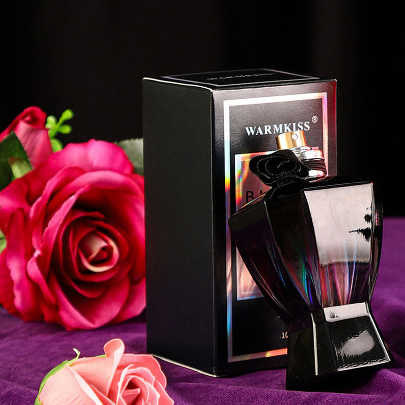 Black perfume bottle with packaging and pink roses on a dark background