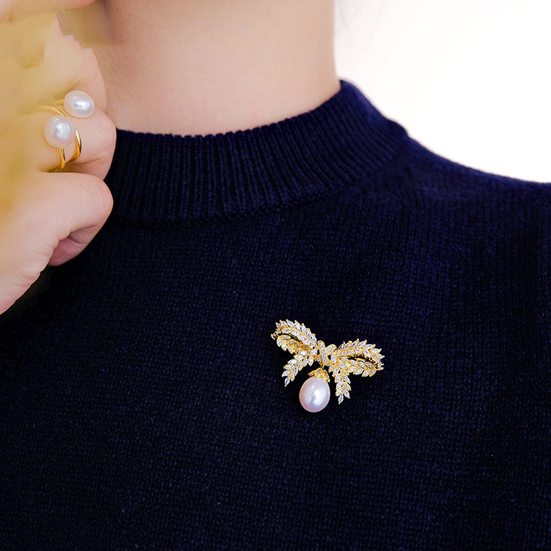 Gold brooch with pearl on a navy sweater