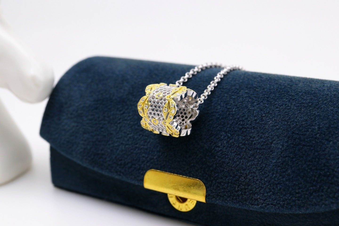Gold and silver necklace on a blue cushion with a white background