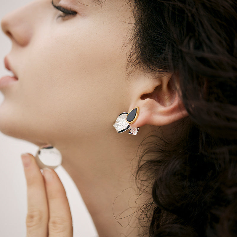 Close-up of a woman wearing a gold and black earring.