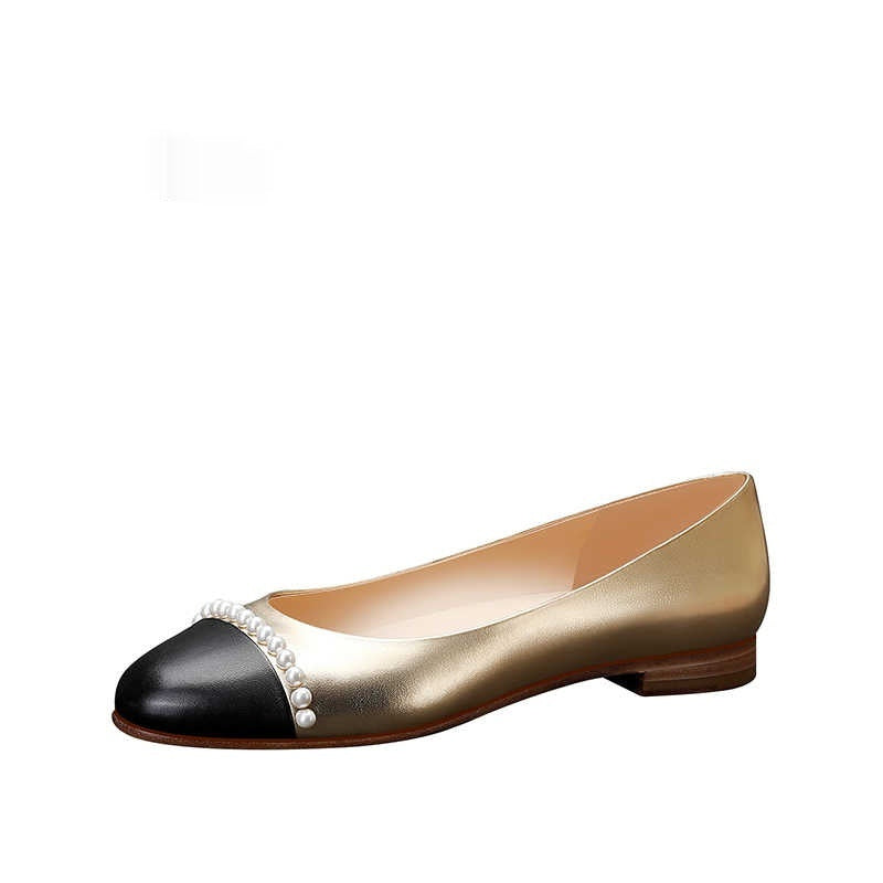 Gold and black flat shoe with pearl embellishments on a white background