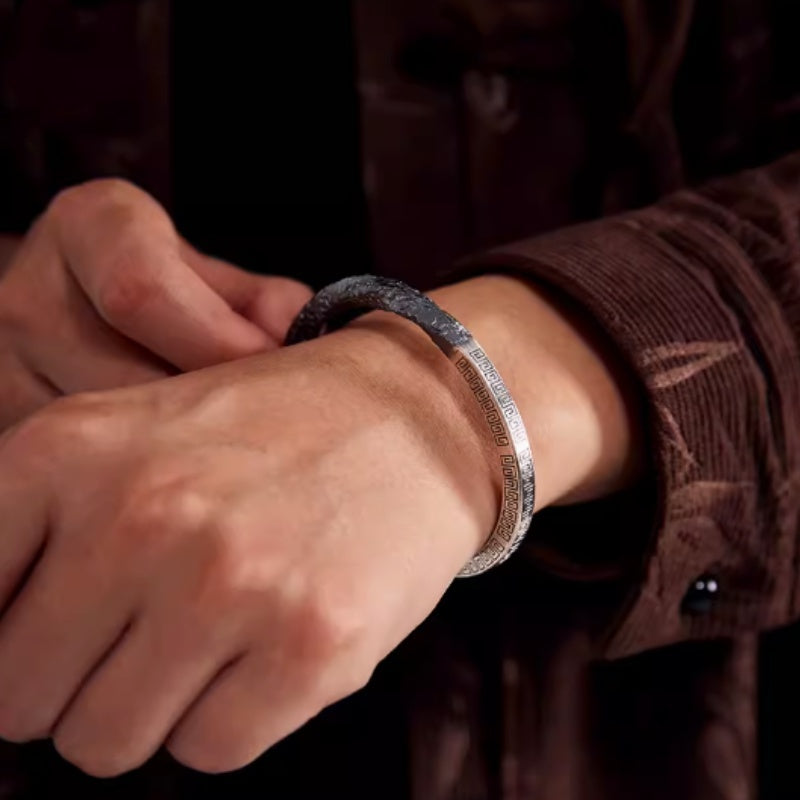 Close-up of a wrist wearing a silver bracelet with a blurred background