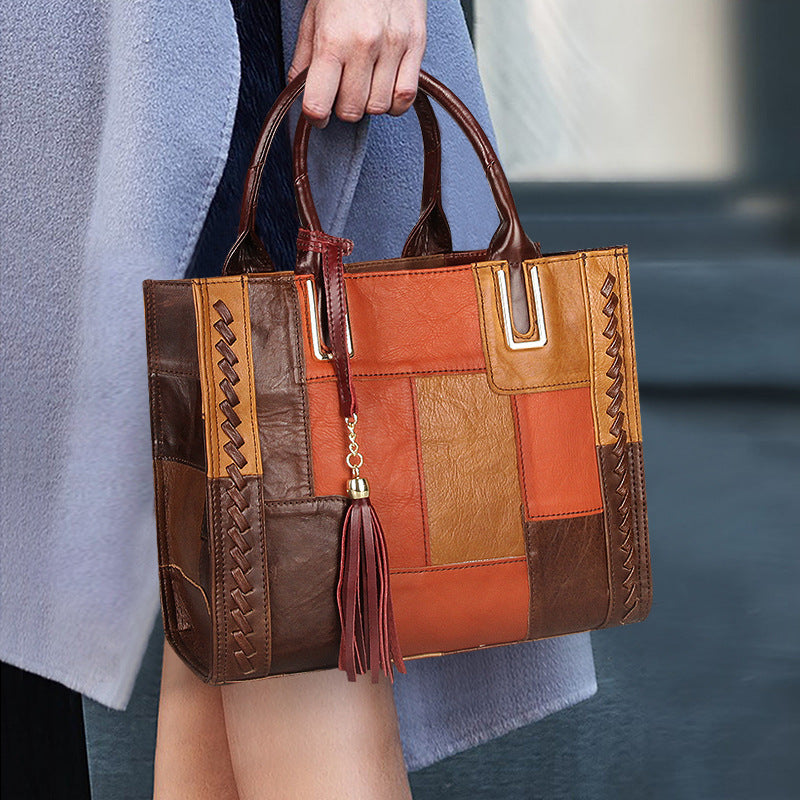 Person holding a patchwork leather handbag with a tassel detail.