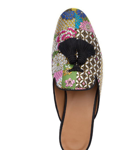 Colorful embroidered sandal with a black tassel on a white background