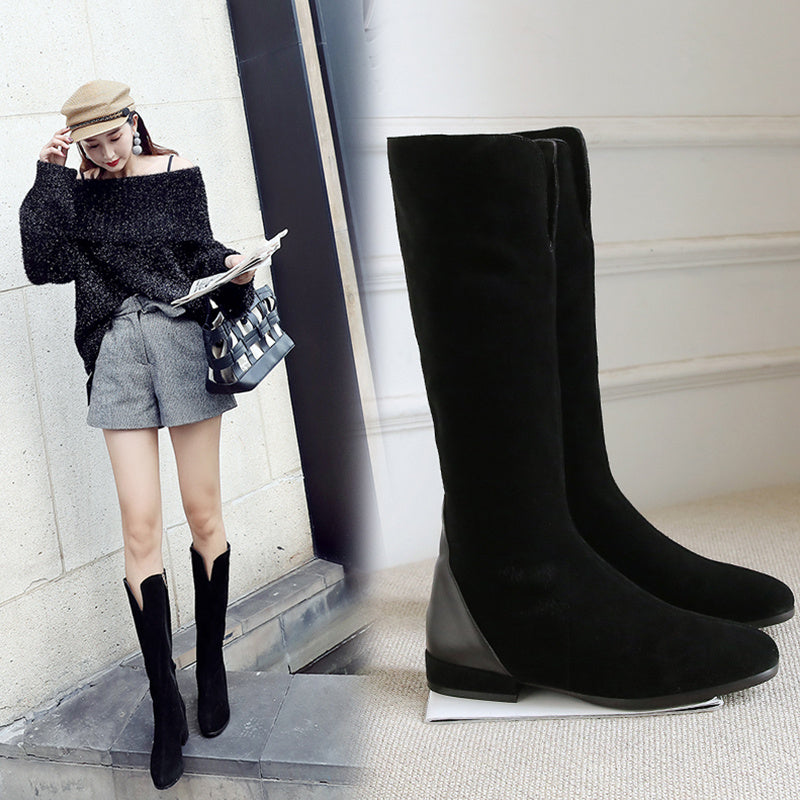 Woman wearing black knee-high boots with a plain background