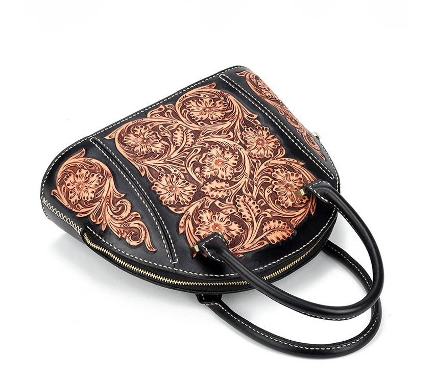 Black handbag with intricate brown leather floral patterns on a white background