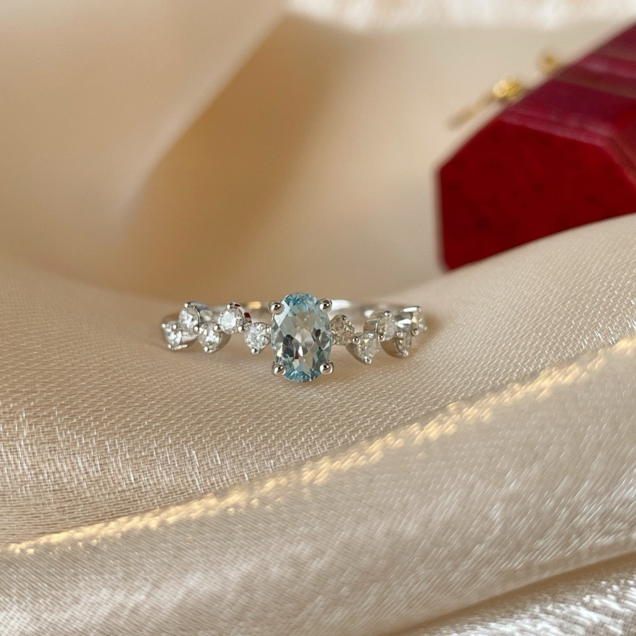 Silver ring with a blue gemstone on a beige fabric background