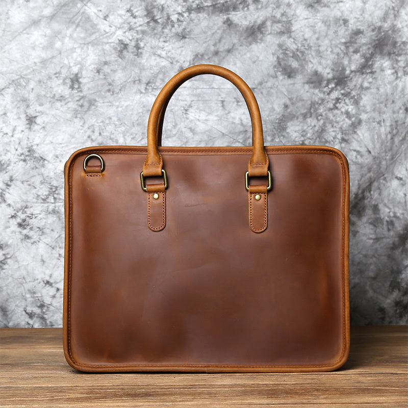 Brown leather briefcase on a wooden surface with a marble background