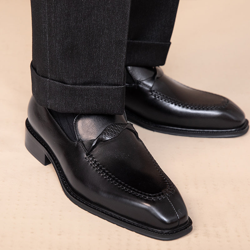 Black leather loafers worn with black pants on a beige background