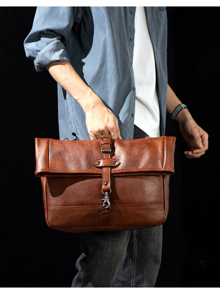 Person holding a brown leather bag against a black background
