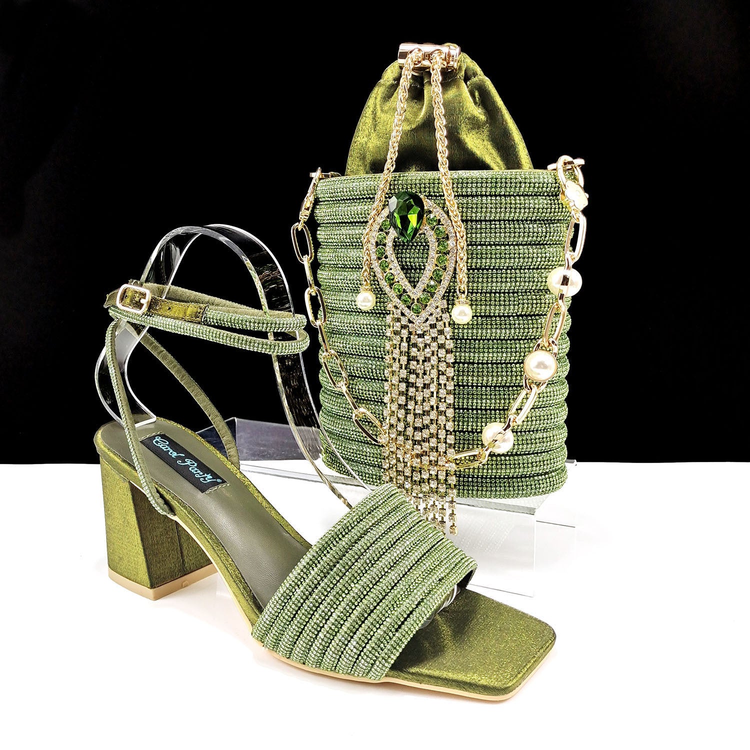Green high-heeled shoe and matching handbag with decorative elements on a white background