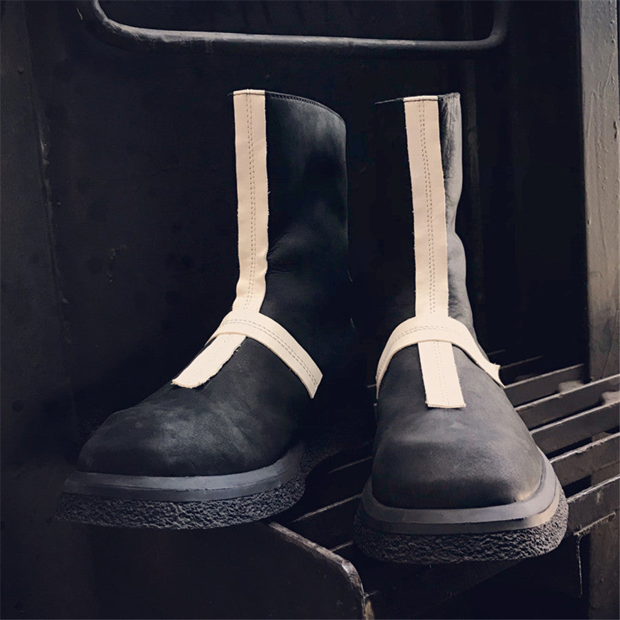 Pair of black boots with white straps on a dark background