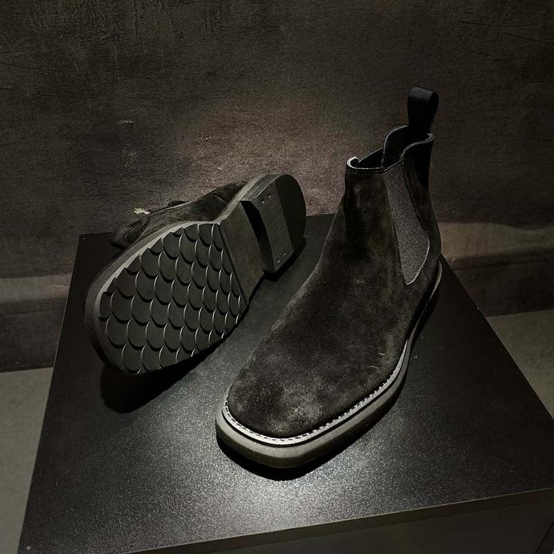 Pair of dark brown leather boots on a black surface with a dark background
