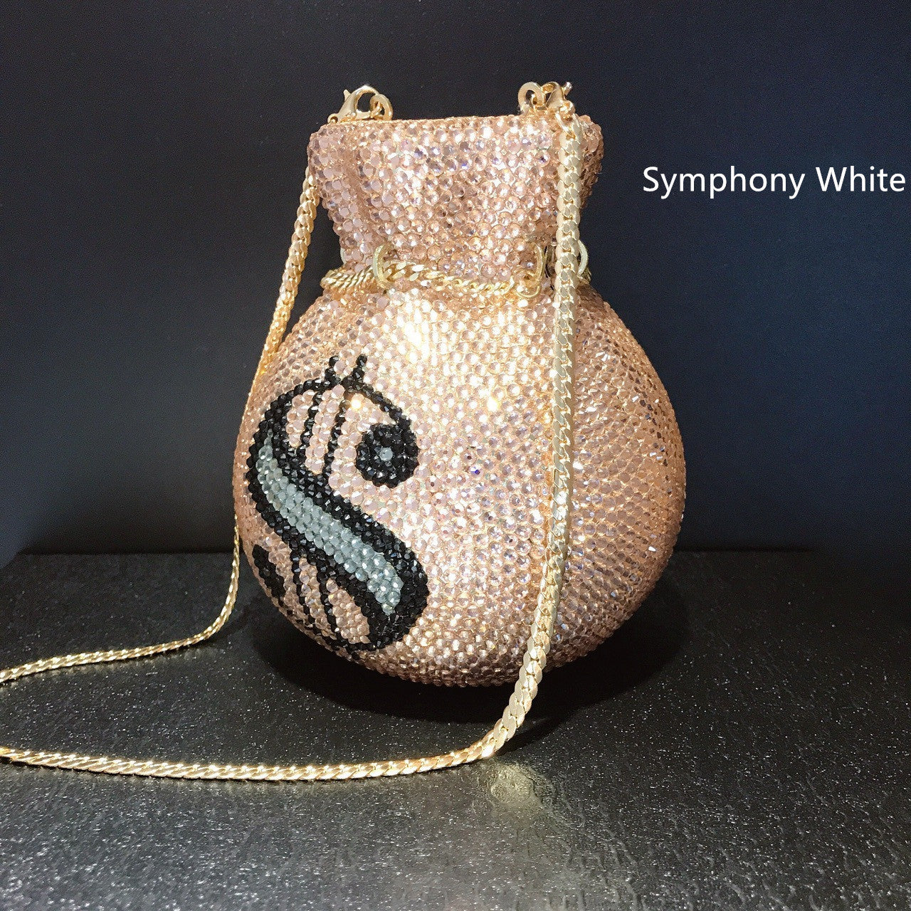 Sparkly handbag with a logo on a dark surface and black background