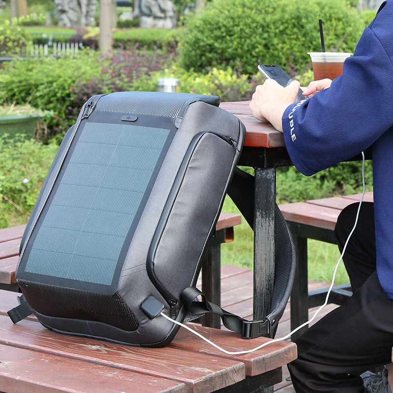 Person using a solar-powered backpack outdoors at a picnic table.
